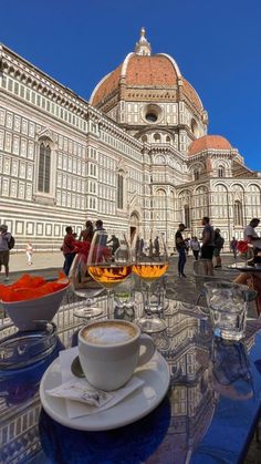 people are standing outside in front of a building with many cups and saucers on the table