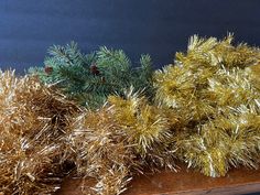 three different types of tinsel and pine needles on a wooden shelf with blue background