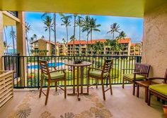 a balcony with chairs, table and view of the pool in the backround