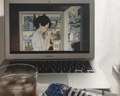 an open laptop computer sitting on top of a desk next to a glass of water