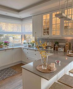 a kitchen with white cabinets and gray counter tops, along with a center island in the middle