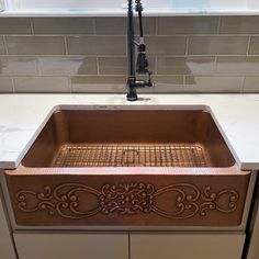 a copper sink in a kitchen under a window