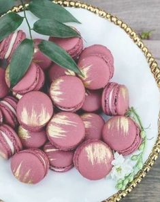 a white plate topped with pink macaroons covered in gold