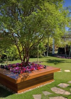 a large wooden planter filled with flowers on top of a lush green park area