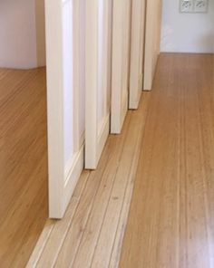 an empty hallway with white walls and wooden flooring is seen in this image from the front door