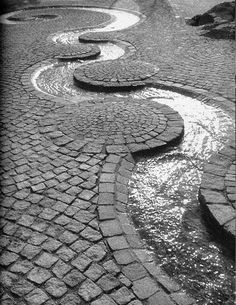 a cobblestone street with stepping stones in the center and water running through it