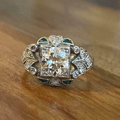 an antique diamond and emerald ring on a wooden table