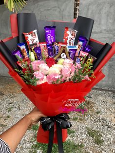 a hand holding a bouquet of flowers and chocolates