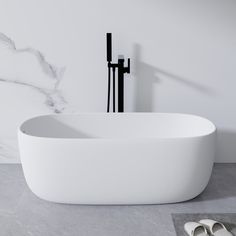 a white bath tub sitting on top of a bathroom floor next to a pair of slippers