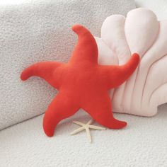 an orange starfish laying on top of a white blanket next to a pink pillow