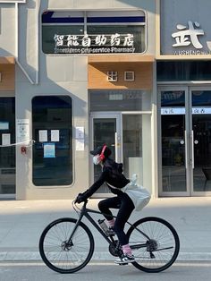 a person riding a bike down the street in front of a building with chinese writing on it