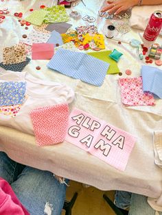 several people sitting at a table with cloths and sewing supplies on top of it