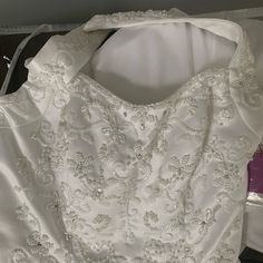 the back of a white wedding dress with beading on it and a purple tag