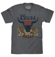 Your New Favorite Tee If you're going to saddle up and ride like a cowboy, you're going to have to look the part. Don't worry though - the Tee Luv team has you covered with a rugged and stylish beer t-shirt that'll work for the ranch and the rodeo! We've selected the instantly recognizable Coors Banquet Rodeo bull logo, and set it against an American frontier inspired desert background. To complete the timeless and authentic western vibe of this Coors Banquet shirt - we've distressed the graphi Coors Rodeo, Rodeo Bull, Coors Banquet, Desert Background, Birthday Things, Desert Scene, American Frontier, Southern Outfits, Bull Logo