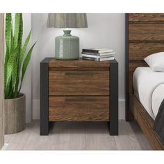 a night stand next to a bed and a plant