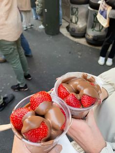 two plastic containers filled with chocolate covered strawberries on top of a street side walk