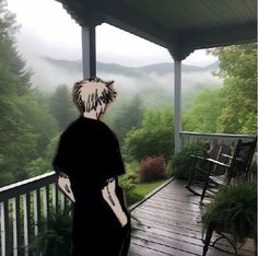 a person standing on a porch looking out at the foggy mountains in the distance