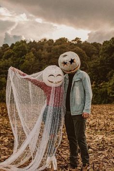 a man and woman standing next to each other in the middle of a field covered with leaves