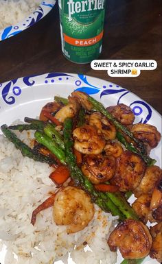 a plate with shrimp, asparagus and rice on it next to a bottle of beer