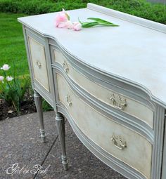 an old dresser is painted white and has pink flowers on the top drawer, along with other antique furniture