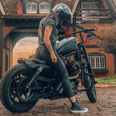 a person sitting on a motorcycle in front of a house