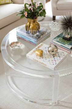 a glass coffee table topped with books and flowers