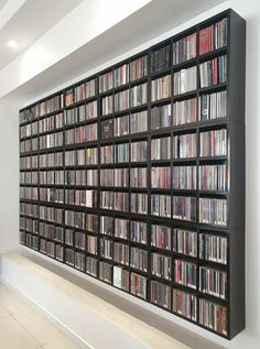 a large book shelf filled with lots of books on top of a white tiled floor