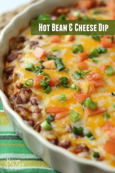 a casserole dish with beans, cheese and green onions in it on a striped cloth