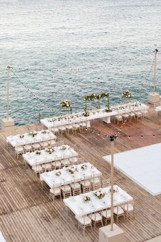 tables and chairs are set up on the deck for an outdoor wedding reception by the water