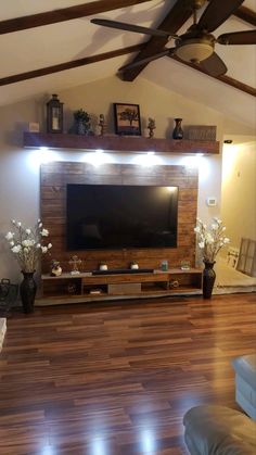 a living room with wooden floors and a flat screen tv mounted on the wall above it