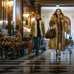 two women in fur coats are walking down the hall