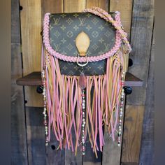 a purse with fringes and beads hanging on a wooden wall