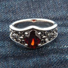 Refined, elegant, and intricate, the style of baroque will appeal to sophisticated men who are not afraid to wear ornate patterns and bright accents. The key element of this Garnet Sterling Silver Band ring is a large blood-red faceted garnet that successfully complements the contrasting colors of polished and blackened silver. A heraldic lily, otherwise knows as fleur de lis, blooms on the sides of the stone. For several centuries, it has been considered a symbol of royal power. Fortunately, yo Blood Ring, Sophisticated Men, Red Garnet Ring, Gothic Ring, Dragon Bracelet, Style Baroque, Garnet Gem, Gothic Rings, Sterling Silver Rings Bands