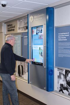 a man standing next to a blue and silver wall mounted display with pictures on it