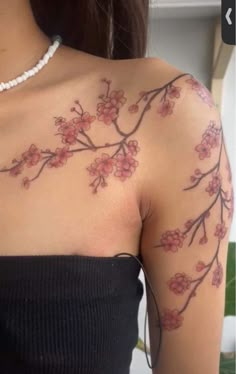 a woman's arm with flowers on it and a beaded necklace hanging from the neck