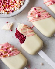 several desserts on sticks with sprinkles and other toppings around them