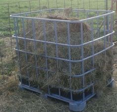 hay in a cage on the side of a field