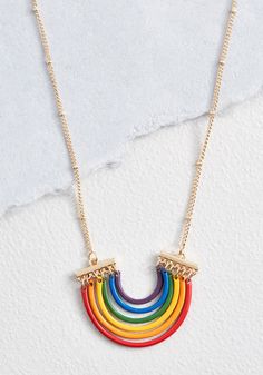 the rainbow necklace is hanging from a gold chain