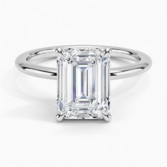 an emerald - cut diamond ring with three clawed shans on the band, set in 18k white gold