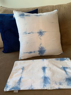 two blue and white pillows sitting on top of a couch