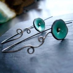 two pairs of green earrings sitting on top of a table