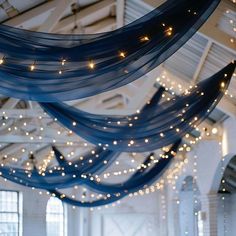 the ceiling is decorated with lights and blue sheer fabric draped from it's sides