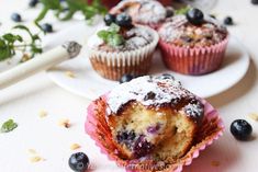 blueberry muffins with powdered sugar and fresh berries on the top, ready to be eaten