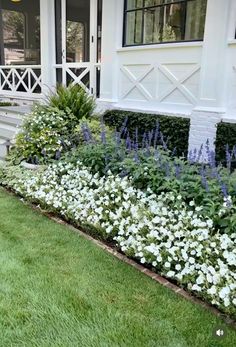 some white flowers and grass in front of a house