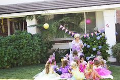 a group of children sitting on the grass in front of a house with balloons and streamers