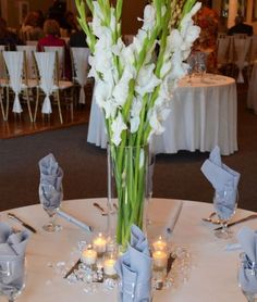 a vase filled with white flowers sitting on top of a table covered in silver napkins