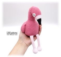 a crocheted pink bird is held in someone's hand with an eye patch