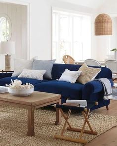 a living room with blue couches and pillows on top of the rugs in front of windows