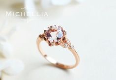 a pink diamond ring sitting on top of a white flowered tablecloth with the words, michellia written below it