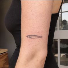 a woman's arm with a small fish tattoo on the left side of her arm